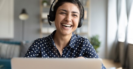 Lachende vrouw achter laptop en een koptelefoon op