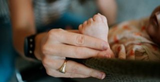 Moeder houdt hand vast van haar pasgeboren baby