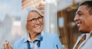 Oudere vrouw en jongeman voeren een gezellig gesprek op een bankje voor een huis