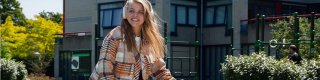 Een jonge vrouw zit lachend op de fiets met een koptelefoon op