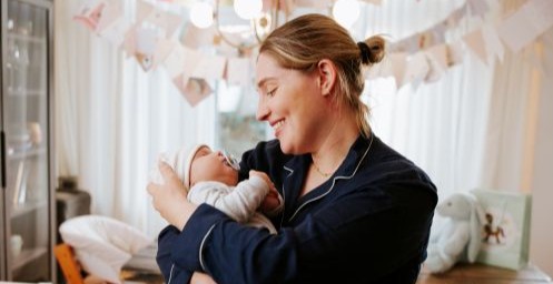 Moeder kijkt blij naar haar pasgeboren baby in haar armen